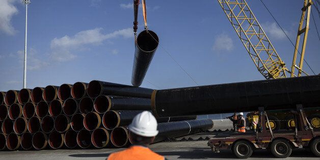 A worker watches as his colleagues use ropes to guide a pipe section for the Trans Adriatic gas pipeline onto a transport truck on the dockside at the cargo port of Alexandroupolis, Greece, on Feb. 23, 2017. The Trans Adriatic Pipeline AG (TAP) will transport Caspian natural gas to Europe crossing Northern Greece, Albania and the Adriatic Sea coming ashore in Southern Italy to connect the Italian gas network to the Trans Anatolian Pipeline (TANAP). Photographer: Konstantinos Tsakalidis/Bloomberg