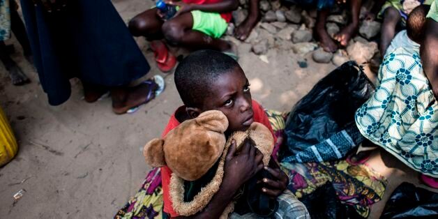 A boy holds his teddy bear as he waits with other Internally Displaced Persons (IDP) for a daily food ration at a camp for IDP's fleeing the conflict in the Kasai Province on June 7, 2017 in Kikwit. / AFP PHOTO / JOHN WESSELS (Photo credit should read JOHN WESSELS/AFP/Getty Images)