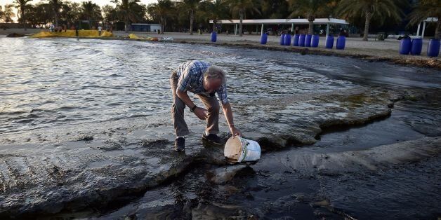 A man tries to clean up oil from a beach in Agios Kosmas at Athens southern suburb on September 13, 2017, after an oil spill from a sunken tanker drifted to other parts of the Saronic Gulf in Athens. The coastguard said an entire bay on the southeast of the island had been affected after the Agia Zoni II, carrying 2,500 metric tonnes of fuel, sank. The spill extends over 1.5 kilometres and the full cleanup will likely require four months, greater Athens fisheries councillor Voula Toutountzi told the capital's municipal radio. / AFP PHOTO / LOUISA GOULIAMAKI (Photo credit should read LOUISA GOULIAMAKI/AFP/Getty Images)