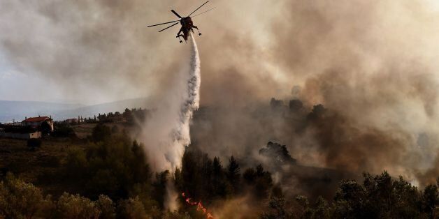 TOPSHOT - A firefighting helicopter drops water on a fire burning east of the Greek capital Athens on August 15, 2017.The army was called in to assist firefighters around Kalamos, 45 kilometres (30 miles) east of Athens, where a fire has been burning since August 13. In all, 146 fires have broken out across Greece since then according to authorities. / AFP PHOTO / ARIS MESSINIS (Photo credit should read ARIS MESSINIS/AFP/Getty Images)