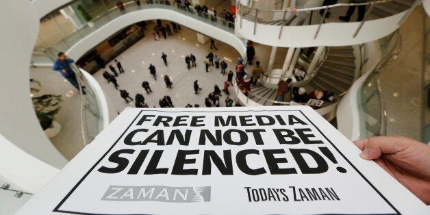 A Zaman journalist holds a banner at the headquarters of Zaman daily newspaper in Istanbul December 14, 2014. Turkish police raided a television station and a newspaper close to U.S.-based Muslim cleric Fethullah Gulen on Sunday, detaining some people, media reports said, two days after President Tayyip Erdogan signalled a fresh campaign against Gulen's supporters. A crowd chanted at the Istanbul offices of newspaper Zaman as editor Ekrem Dumanli made a speech to them broadcast live on television, defiantly calling on police to detain him. REUTERS/Murad Sezer (TURKEY - Tags: CIVIL UNREST POLITICS MEDIA TPX IMAGES OF THE DAY)