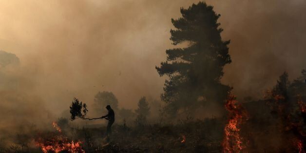 TOPSHOT - Firemen and volunteers try to extinguish a fire east of the Greek capital Athens on August 15, 2017. The army was called in to assist firefighters around Kalamos, 45 kilometres (30 miles) east of Athens, where a fire has been burning since August 13. In all, 146 fires have broken out across Greece since then according to authorities. / AFP PHOTO / ARIS MESSINIS (Photo credit should read ARIS MESSINIS/AFP/Getty Images)