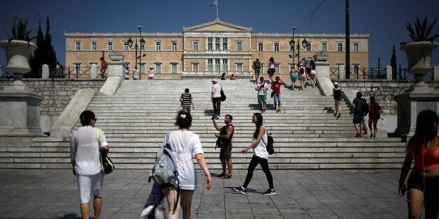 People make their way on main Syntagma square as the parliament building is seen in the background in Athens, Greece, July 24, 2017. REUTERS/Alkis Konstantinidis
