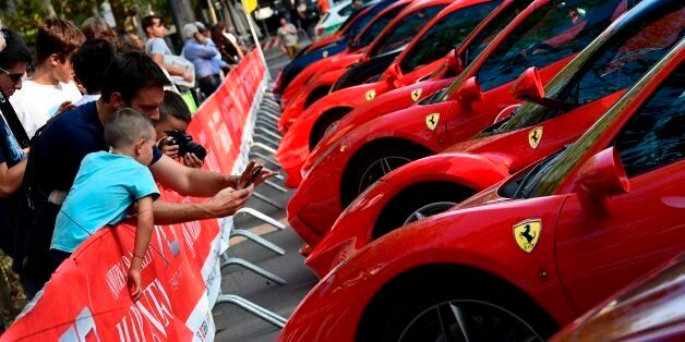 People take photos of Italian Ferrari automobiles on display at the Corso Sempione in Milan before taking to the road towards Maranello, the home of Ferrari, to celebrate the Prancing Horse's 70th anniversary, on September 8, 2017. / AFP PHOTO / MIGUEL MEDINA (Photo credit should read MIGUEL MEDINA/AFP/Getty Images)