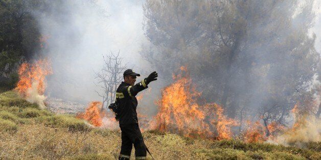 ATHENS, GREECE - AUGUST 15: Firefighters battle with a wildfire which has been continuing for two days, in Kalamos region of Athens, Greece on August 15, 2017. High winds are driving wildfires near the Greek capital Athens, forcing residents and holidaymakers to flee. More than 20 houses have already been damaged as the blazes, which began on Sunday, burned through pine forests north of the city. Around 150 firefighters, with the help of helicopters and planes, are still battling to contain fires in the coastal areas of Kalamos and Varnava. (Photo by Ayhan Mehmet/Anadolu Agency/Getty Images)