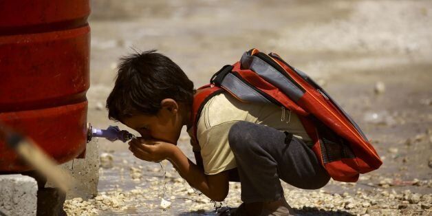 TOPSHOT - A displaced child from the Islamic State (IS) group's Syrian stronghold of Raqa, drinks water as he head to attend the first day of the new school year at a camp for internally displaced people in Ain Issa on August 22, 2017. / AFP PHOTO / Delil souleiman (Photo credit should read DELIL SOULEIMAN/AFP/Getty Images)