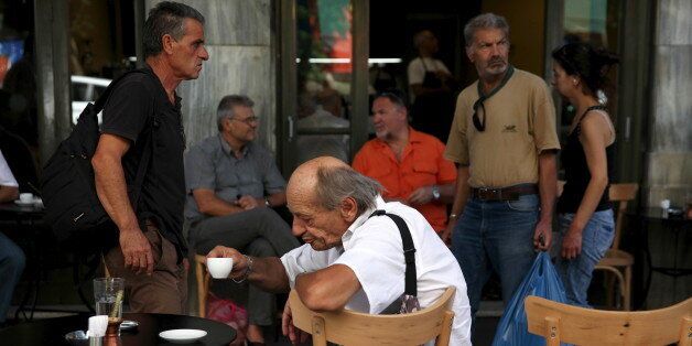 People sit outside a coffee shop in central Athens, Greece, July 20, 2015. Greece reopened its banks and started the process of paying off billions of euros owed to international creditors on Monday in the first signs of a return to normal after a deal to agree a new package of bailout reforms. Increases in value added tax agreed under the bailout terms also took effect, with VAT on food and public transport jumping to 23 percent from 13 percent. The stock market remained closed until further notice. REUTERS/Yiannis Kourtoglou