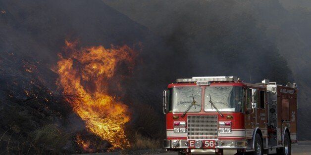 SUNLAND CA SEPTEMBER 2, 2017 --- A fire truck passes by burning brush along La Tuna Canyon Road that is closed to traffic. La Tuna brush fire in the Verdugo Mountains north of Los Angeles grew to 5,000 acres on Saturday morning, threatening homes and keeping the 210 Freeway closed. Hundreds of firefighters battled the blaze overnight and into the morning, and at one point the flames were spreading in four directions at once amid intense heat and wild winds. (Photo by Irfan Khan/Los Angeles Tim