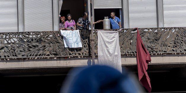 ROME, ITALY - AUGUST 23: Refugees with gas cylinders on a balcony of thepalace as they protest whend police try to remove refugees who camped in Piazza Indipendenza Gardens after their eviction from an occupied building in Piazza Indipendenza, on August 23, 2017 in Rome, Italy. From Saturday about 200 immigrants, all with regular residence permits and with the status of refugee and Prevenienti from Eritrea and Ethiopia, have camped in the street waiting to understand what will now be their destiny. About a hundred remain, including vulnerable families. The United Nations High Commissioner for Refugees (UNHCR) expresses 'particular concern about the lack of alternatives for most vacated persons'. (Photo by Stefano Montesi - Corbis/Corbis via Getty Images)