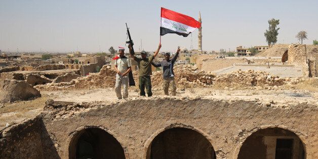 Fighters from the Hashed al-Shaabi (Popular Mobilisation units), backing the Iraqi forces, pose with the Iraqi flag from Tal Afar's Ottoman-era historic citadel after troops took control of the area during an operation to retake the city from the Islamic State (IS) group on August 27, 2017.Iraqi forces backed by local militia and a US-led coalition were poised to drive the Islamic State group from Tal Afar, dealing another blow to the jihadists. / AFP PHOTO / AHMAD AL-RUBAYE (Photo credit should read AHMAD AL-RUBAYE/AFP/Getty Images)