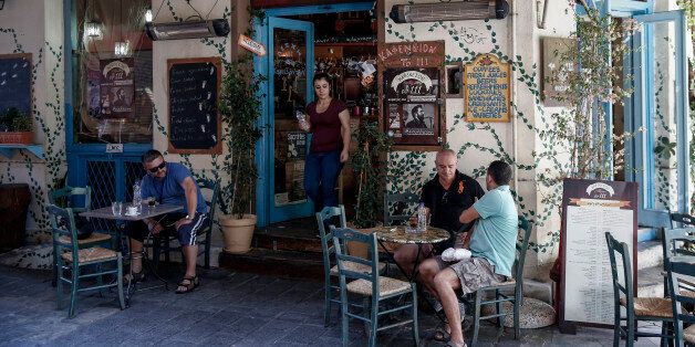Customers sit and drink beverages at outdoor tables at a cafe in the Psyri neighborhood of Athens, Greece, on Friday, July 17, 2015. Germany's Parliament is set to ratify bridge financing and the start of talks for a three-year rescue plan. Photographer: Yorgos Karahalis/Bloomberg via Getty Images