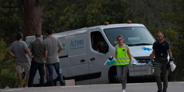 Forensic police members carry a box with evidences past the van of the funeral services carrying the body of Moroccan suspect Younes Abouyaaqoub on the site where he was shot on August 21, 2017 in Subirat, near Sant Sadurni d'Anoia, south of Barcelona, four days after the Barcelona and Cambrils attacks that killed 15 people.Spanish police said on August 21, 2017 that they have identified the driver of the van that mowed down pedestrians on the busy Las Ramblas boulevard in Barcelona, killing 13.The 22-year-old Moroccan Younes Abouyaaqoub is believed to be the last remaining member of a 12-man cell still at large in Spain or abroad, with the others killed by police or detained over last week's twin attacks in Barcelona and the seaside resort of Cambrils that claimed 14 lives, including a seven-year-old boy. / AFP PHOTO / LLUIS GENE (Photo credit should read LLUIS GENE/AFP/Getty Images)