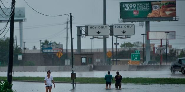 TOPSHOT - People walk dogs through flooded streets as the effects of Hurricane Harvey are seen August 27, 2017 in Galveston, Texas.Hurricane Harvey left a trail of devastation Saturday after the most powerful storm to hit the US mainland in over a decade slammed into Texas, destroying homes, severing power supplies and forcing tens of thousands of residents to flee. / AFP PHOTO / Brendan Smialowski (Photo credit should read BRENDAN SMIALOWSKI/AFP/Getty Images)