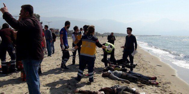 TOPSHOT - EDITORS NOTE: Graphic content / -- TURKEY OUT --Migrants bodies are washed up on a beach as first aid officials work on the site on March 24, 2017 in Izmir, in Kusadasi district. Eleven people drowned and four were missing after a migrant boat sank off Turkey's Aegean coast on March 24, local media reported. The bodies of the dead were found on a shore in the western province of Aydin, the private Dogan news agency reported. / AFP PHOTO / DOGAN NEWS AGENCY / Latif SANSUR / Turkey OUT (Photo credit should read LATIF SANSUR/AFP/Getty Images)