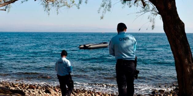 Portugese officers serving for the European Border and Coast Guard Agency look at a rubber boat from a recent refugee arrival during their patrol in Skala Sykamias, at the north part of the island of Lesbos on March 28, 2017. The agency, built on the foundations laid by Frontex, continues to support Greece in border surveillance, search and rescue, registration and identification of the migrants, but it also assists the Greek authorities in returns and readmissions from the hotspots. / AFP PHOTO / LOUISA GOULIAMAKI (Photo credit should read LOUISA GOULIAMAKI/AFP/Getty Images)