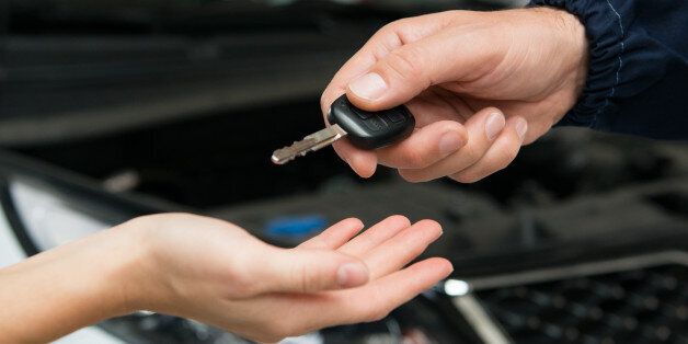 Closeup Of Mechanic Giving Car Key To Customer At Garage