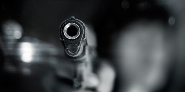 Black and white, woman pointing a old gun to front with one Hand on dark background