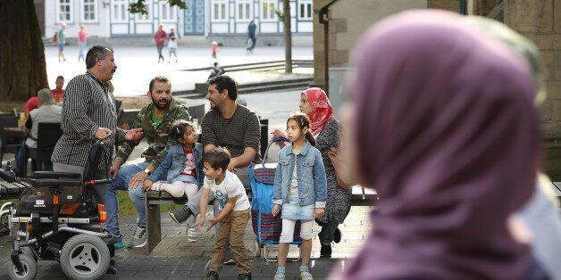 GOSLAR, GERMANY - AUGUST 25: A family who said they are from the Syrian city of Homs relax on a bench in the historic city center as two women wearing headscarves walk past on August 25, 2017 in Goslar, Germany. City authorities in Goslar promoted a particularly open policy towards welcoming refugees in the large tide that reached Germany in 2015, as they saw the newcomers not only as a humanitarian responsibility but also as an opportunity for countering the region's demographic and economic decline. Today migrants and refugees of diverse origins seem to make up a natural element to the town's human fabric. Germany is holding federal elections on September 24 and refugee policy remains a contentious political issue. Germany took in over one million refugees and migrants between 2015 and 2016. (Photo by Sean Gallup/Getty Images)