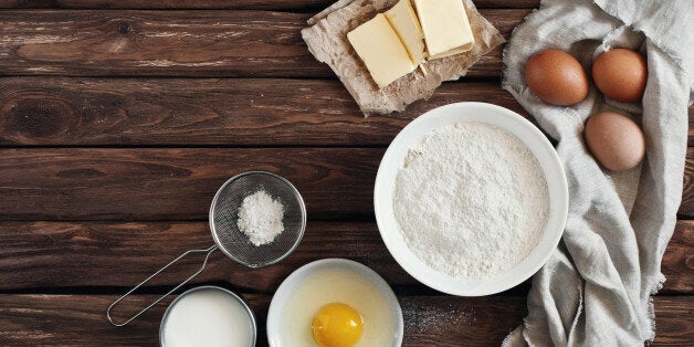 ingredients for making pancakes or cake - flour, egg, butter, milk on the old wooden background. top view. rustic or rural style. background with free text space. Ingredients for the dough.