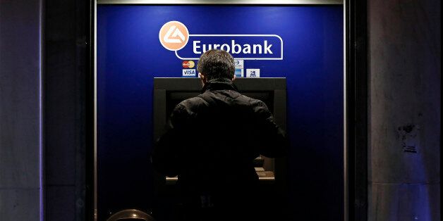 A customer uses an automated teller machines (ATM) operated by Eurobank Ergasias SA at night in Athens, Greece, on Tuesday, Nov. 3, 2015. Greece's four biggest banks may need as little as 1.2 billion euros ($1.3 billion) of new private funds to meet their expected contributions toward filling a capital shortfall, if they succeed in raising 3.2 billion euros through debt swaps. Photographer: Kostas Tsironis/Bloomberg via Getty Images
