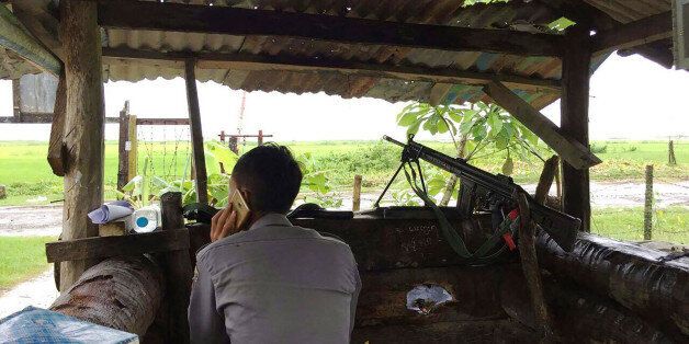 A Myanmar policeman talks on the phone as he mans a check point at the entrance of Yathae Taung township...