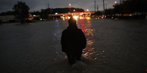 HOUSTON, TX - AUGUST 29: A Houston resident walks through waist deep water while evacuating her home after severe flooding following Hurricane Harvey in north Houston August 29, 2017 in Houston, Texas. Harvey, which made landfall north of Corpus Christi late Friday evening, is expected to dump upwards of 40 inches of rain over the next couple of days. (Photo by Win McNamee/Getty Images)