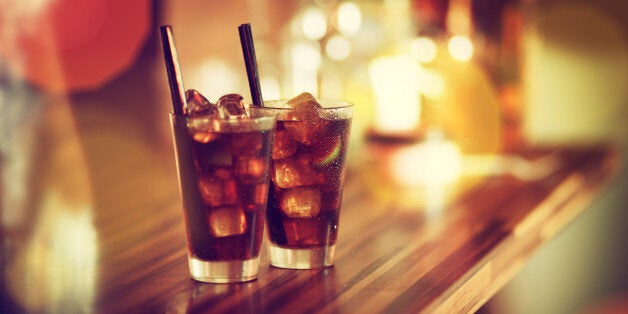 Two glasses of rum-cola cocktail with ice served on the bar. Vintage colour look.