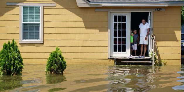 A family stand in the door of their flooded house in Port Arthur, Texas, U.S., August 31, 2017. REUTERS/Carlo Allegri