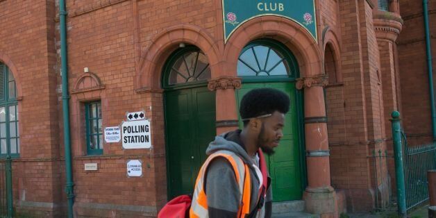 A postman walks past a polling station sign on the Salford Lads Club on Coronation Street where voting in the Greater Manchester mayoral election is taking place, in Manchester, northern England on May 4, 2017. / AFP PHOTO / OLI SCARFF (Photo credit should read OLI SCARFF/AFP/Getty Images)