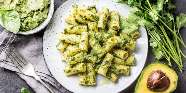 Vegetarian green pasta with avocado and herbs sauce on slate background