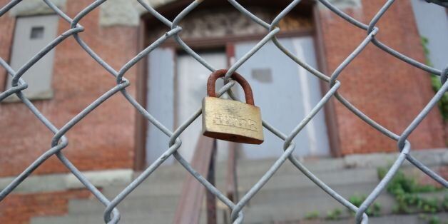 A padlock is clipped to the fence of a closed public schoolhouse on May 30, 2017 in Newburgh, New York.Rows of boarded-up homes became a ubiquitous symbol of the US housing crash. Some 10 years later, the national market has recovered, and although the bricks and mortar scars of abandoned properties remain in many states, suitors are lining up in some places where tumbleweed has long outgrown the market. Newburgh, a once thriving area of 30,000 people succumbed to rising interest rates, falling prices and local tax hikes. Many families moved without warning in 2007-08. Vacant properties remain, but Newburgh is on the up. / AFP PHOTO / Don EMMERT (Photo credit should read DON EMMERT/AFP/Getty Images)