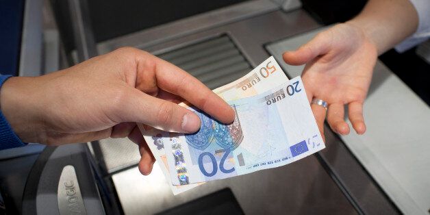 BONN, GERMANY - JULY 04: A shopper paying in cash at the supermarket check-out pictured on July 04, 2013 in Bonn, Germany. (Photo by Ute Gabrowsky/Photothek via Getty Images)