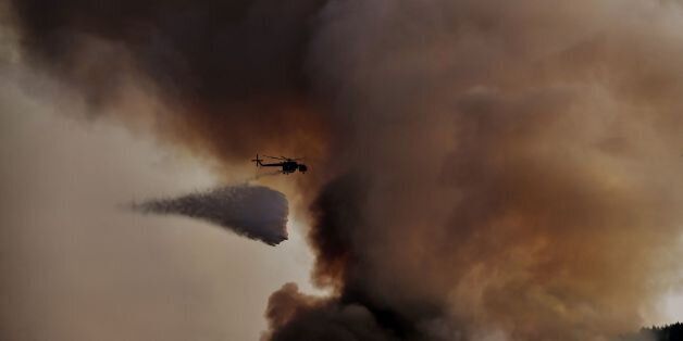 A firefighting helicopter drops waters over a fire, east of the Greek capital Athens on August 15, 2017. The army was called in to assist firefighters around Kalamos, 45 kilometres (30 miles) east of Athens, where a fire has been burning since August 13. In all, 146 fires have broken out across Greece since then according to authorities. / AFP PHOTO / ARIS MESSINIS (Photo credit should read ARIS MESSINIS/AFP/Getty Images)