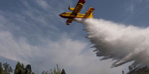 VILA DE REI, PORTUGAL - AUGUST 15: A Canadair CL-215 (Scooper) firefighting amphibious aircraft drops water over the historical village of Agua Formosa on August 15, 2017 in Vila de Rei, Portugal. More than a thousand firefighters and military personnel have joined efforts trying to control the numerous fires in the country. The Portuguese government has asked for EU help to combat hundreds of forest fires in both Centro and Norte regions of the country. (Photo by Horacio Villalobos - Corbis/Corbis via Getty Images)