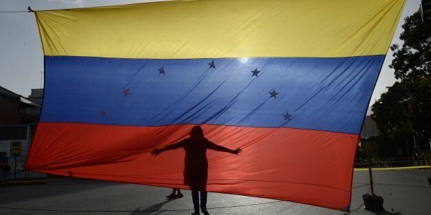 TOPSHOT - A person's shadow is cast on a Venezuelan national flag in Caracas on July 10, 2017.Venezuela hit its 100th day of anti-government protests Sunday, amid uncertainty over whether the release from prison a day earlier of prominent political prisoner Leopoldo Lopez might open the way to negotiations to defuse the profound crisis gripping the country. / AFP PHOTO / FEDERICO PARRA (Photo credit should read FEDERICO PARRA/AFP/Getty Images)