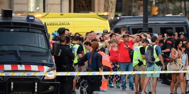 Policemen check the identity of people standing with their hands up after a van ploughed into the crowd, killing two persons and injuring several others on the Rambla in Barcelona on August 17, 2017.A driver deliberately rammed a van into a crowd on Barcelona's most popular street on August 17, 2017 killing at least two people before fleeing to a nearby bar, police said. Officers in Spain's second-largest city said the ramming on Las Ramblas was a 'terrorist attack' and a police source said one suspect had left the scene and was 'holed up in a bar'. The police source said they were hunting for a total of two suspects. / AFP PHOTO / Josep LAGO (Photo credit should read JOSEP LAGO/AFP/Getty Images)