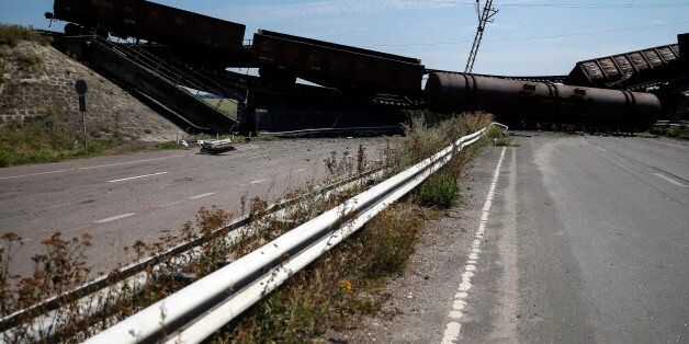 Train wagons are seen on the destroyed railway bridge which collapsed during the fighting between the Ukrainian army and pro-Russian separatists, over a main road leading to the eastern Ukrainian city of Donetsk, near the village of Novobakhmutivka, north of Donetsk city, August 27, 2014. REUTERS/Gleb Garanich (UKRAINE - Tags: POLITICS CIVIL UNREST TRANSPORT)