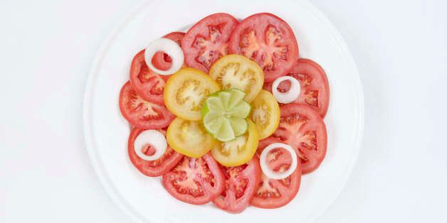 TORONTO, ONTARIO, CANADA - 2016/09/22: Tomato salad garnished with onion rings and a piece of lime. (Photo...