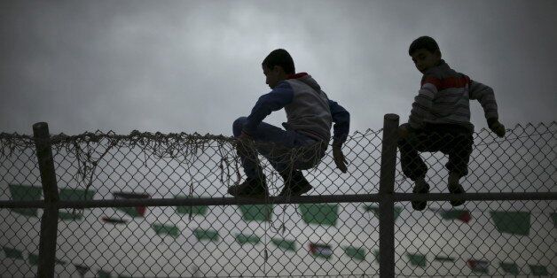 Palestinian boys sit on a fence as they watch a Hamas rally in Khan Younis in the southern Gaza Strip January 7, 2016. The rally, organized by Hamas movement, was held to honor the families of dead Hamas militants, who Hamas's armed wing said participated in imprisoning Israeli soldier Gilad Shalit, organizers said. Shalt was abducted by militants in a cross-border raid in 2006, and was released in exchange for more than 1,000 Palestinians held in Israeli jails. REUTERS/Mohammed Salem