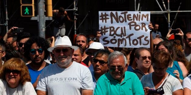 A person holds a sign reading 'We are not afraid. Barcelona, we are all' as he and others wait before observing a minute of silence for the victims of the Barcelona attack at Plaza de Catalunya on August 18, 2017, a day after a van ploughed into the crowd, killing 13 persons and injuring over 100 on the Rambla in Barcelona.Drivers have ploughed on August 17, 2017 into pedestrians in two quick-succession, separate attacks in Barcelona and another popular Spanish seaside city, leaving 13 people dead and injuring more than 100 others. In the first incident, which was claimed by the Islamic State group, a white van sped into a street packed full of tourists in central Barcelona on Thursday afternoon, knocking people out of the way and killing 13 in a scene of chaos and horror. Some eight hours later in Cambrils, a city 120 kilometres south of Barcelona, an Audi A3 car rammed into pedestrians, injuring six civilians -- one of them critical -- and a police officer, authorities said. / AFP PHOTO / LLUIS GENE (Photo credit should read LLUIS GENE/AFP/Getty Images)