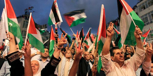Palestinians gesture and wave flags before a public screening of Palestinian President Mahmoud Abbas' speech at the United Nations, in the West Bank city of Ramallah September 23, 2011. Abbas asked the United Nations on Friday to recognize a state for his people, even though Israel still occupies its territory and the United States has vowed to veto the move. REUTERS/Darren Whiteside (WEST BANK - Tags: POLITICS)