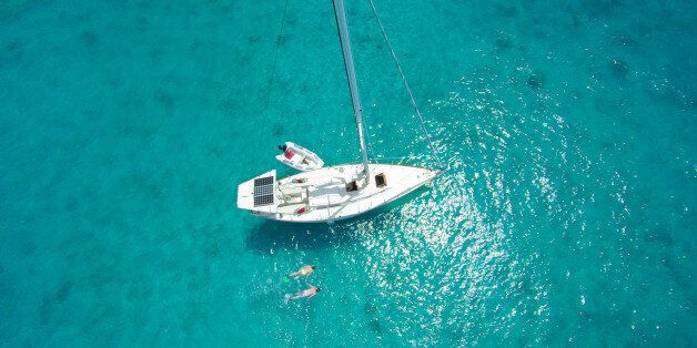 aerial view of honeymoon couple snorkeling next to the sailboat moored in the Caribbean