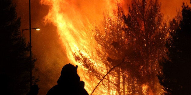 KALAMOS, GREECE - 2017/08/14: A firefighter sprays water during a forest fire in the village of Kalamos. (Photo by Christos Ntountoumis/SOPA Images/LightRocket via Getty Images)