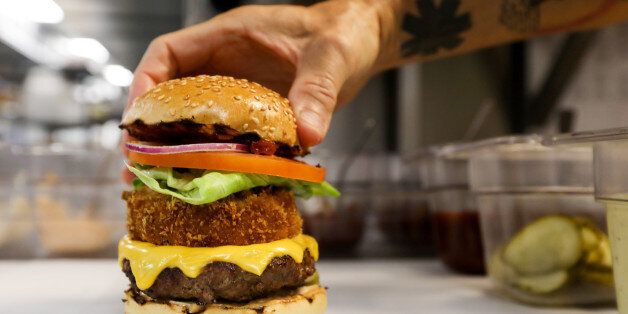 A chef with Gourmet Burger Kitchen (GBK) Ltd. delivery-only kitchen, places the top of a bun on a burger at a Deliveroo Editions field kitchen, operated by Roofoods Ltd., in Hove, U.K., on Wednesday, Aug. 9, 2017. Deliveroo, which hasÂ receivedÂ $475 million in venture funding, began rolling out field kitchens to 30 locations throughout the U.K., allowing customers in new locations to order food from popular upscale restaurant chains such as MEATLiquor, Gourmet Burger Kitchen, and Busaba Eathai, the company announced in April. Photographer: Luke MacGregor/Bloomberg via Getty Images