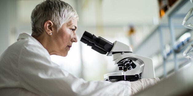 Low angle view of a mature scientist looking through a microscope in a laboratory.