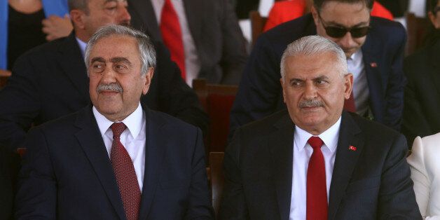 Turkish Cypriot leader Mustafa Akinci (L) and Turkish Prime Minister Binali Yildirim are seen during a parade to mark the 1974 Turkish invasion of Cyprus in response to a briefly lived Greek-inspired coup, in the Turkish-administered northern part of Nicosia, Cyprus July 20, 2017. REUTERS/Yiannis Kourtoglou