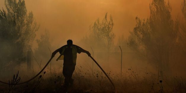 A firefighter works to extinguish a fire east of the Greek capital Athens on August 15, 2017. The army was called in to assist firefighters around Kalamos, 45 kilometres (30 miles) east of Athens, where a fire has been burning since August 13. In all, 146 fires have broken out across Greece since then according to authorities. / AFP PHOTO / ARIS MESSINIS (Photo credit should read ARIS MESSINIS/AFP/Getty Images)