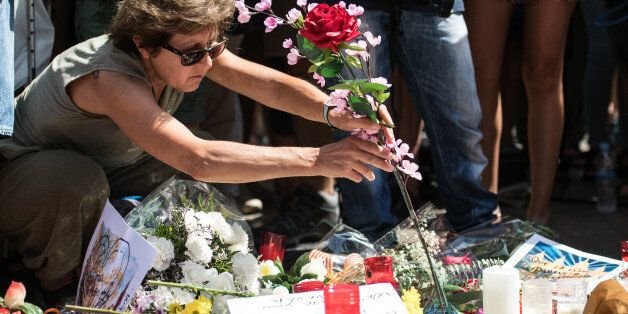 BARCELONA, SPAIN - AUGUST 18: A woman lays a flower on Las Ramblas near the scene yesterday's terrorist attack, on August 18, 2017 in Barcelona, Spain. Fourteen people were killed and dozens injured when a van hit crowds in the Las Ramblas area of Barcelona on Thursday. Spanish police have also killed five suspected terrorists in the town of Cambrils to stop a second terrorist attack. (Photo by Carl Court/Getty Images)