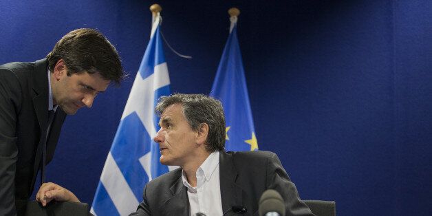 Euclid Tsakalotos, Greece's finance minister, right, speaks with a member of his team before the start of a press conference after a Eurogroup meeting in Brussels, Belgium, on Monday, May 9, 2016. The euro area and the International Monetary Fund will assess whether Greek Prime Minister Alexis Tsipras has made enough budget-tightening commitments to gain another disbursement of emergency loans. Photographer: Jasper Juinen/Bloomberg via Getty Images