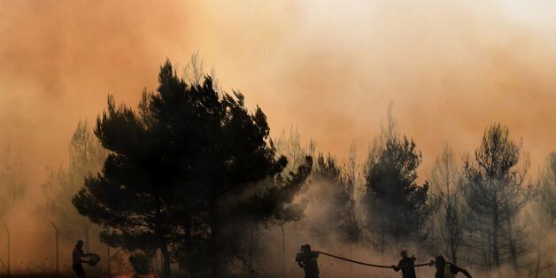Firemen and volunteers try to extinguish a fire east of the Greek capital Athens on August 15, 2017. The army was called in to assist firefighters around Kalamos, 45 kilometres (30 miles) east of Athens, where a fire has been burning since August 13. In all, 146 fires have broken out across Greece since then according to authorities. / AFP PHOTO / ARIS MESSINIS (Photo credit should read ARIS MESSINIS/AFP/Getty Images)
